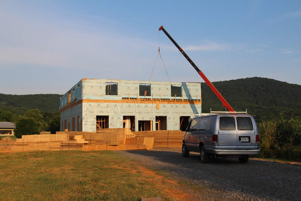 JUNE 13-all panels of east wall are in place. Bundles of roof trusses are in front of temple.