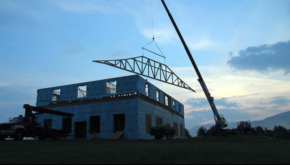 JULY 14-At dawn, first west roof truss is lifted into position.