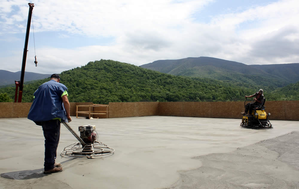 3 MAY&mdash;Workers smoothing concrete with trowel rider and push trowel.