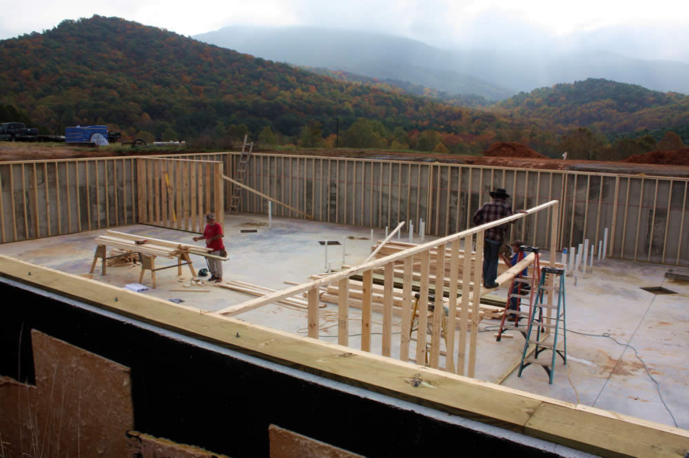 Framing of walls for basement rooms and horizontal supports for steel beams. The diamond-shaped cut-away areas on the floor are the locations for vertical support beams.