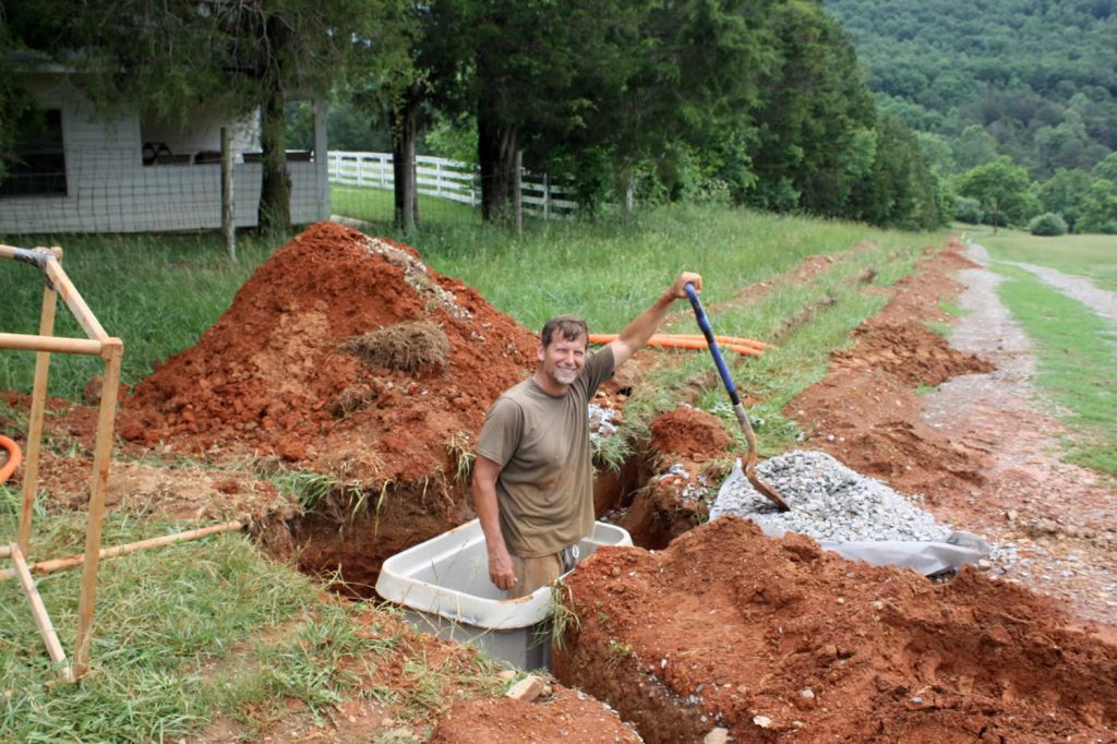 Dean Baker shoveling gravel around the hand-hole to help with drainage