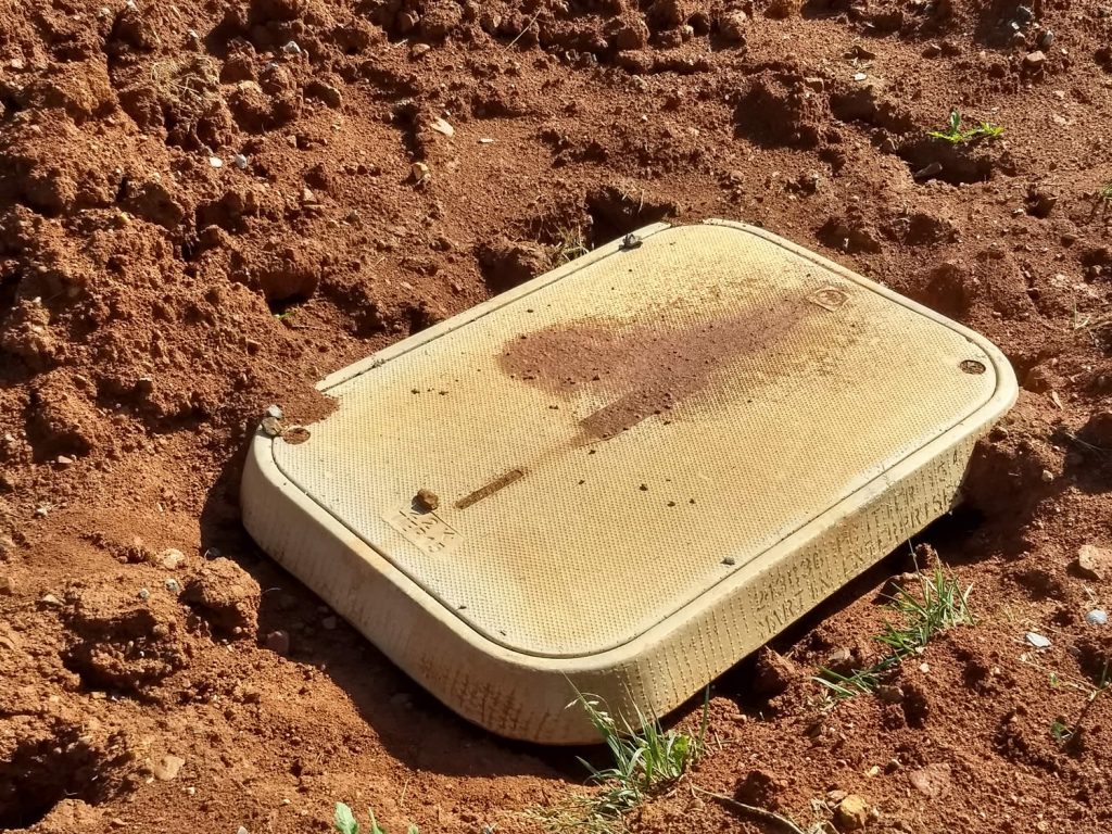 This hand-hole (1 of 8 on the land) is buried flush with the ground and accessible if needed to repair cables or connections.