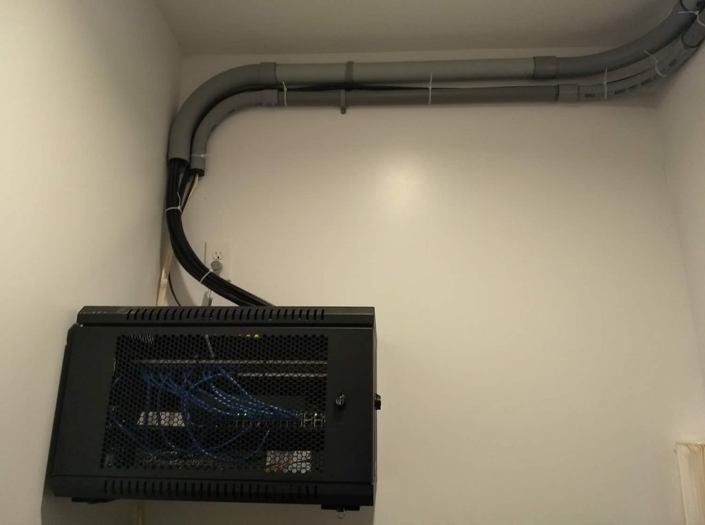 Small conduit brings fiber optic cable into server from the handhole, while the larger conduit takes a bundle of cat6 cables out
